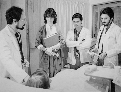 Dr. Joel Deitz teaches residents and medical students from a patient's bedside. c1980-89