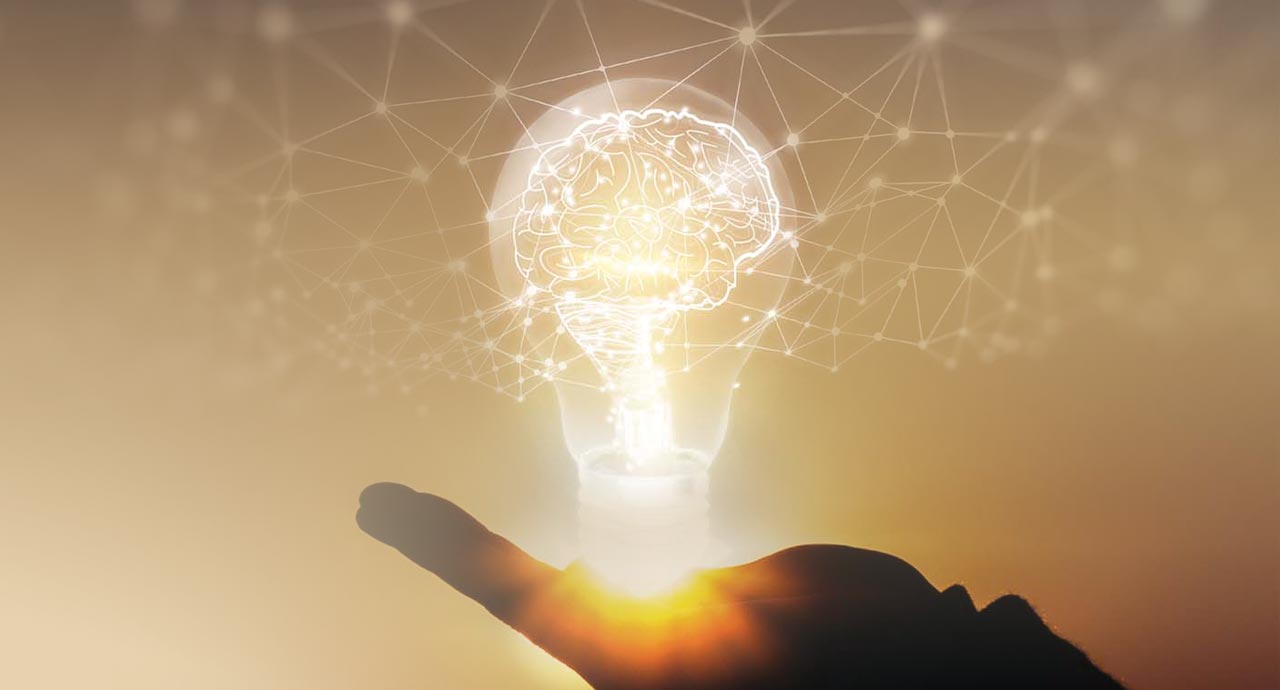 photo illustration of hand holding a bright lightbulb with a brain in it