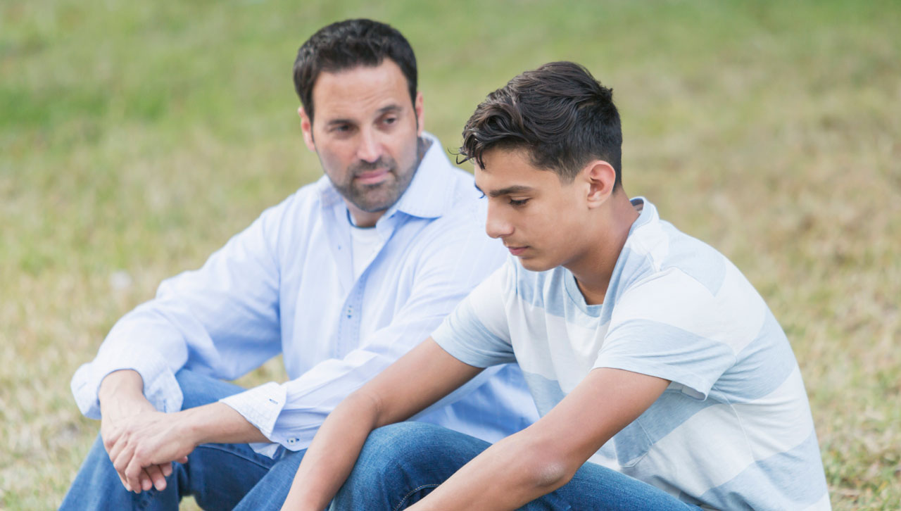 Photo of father talking with teen son