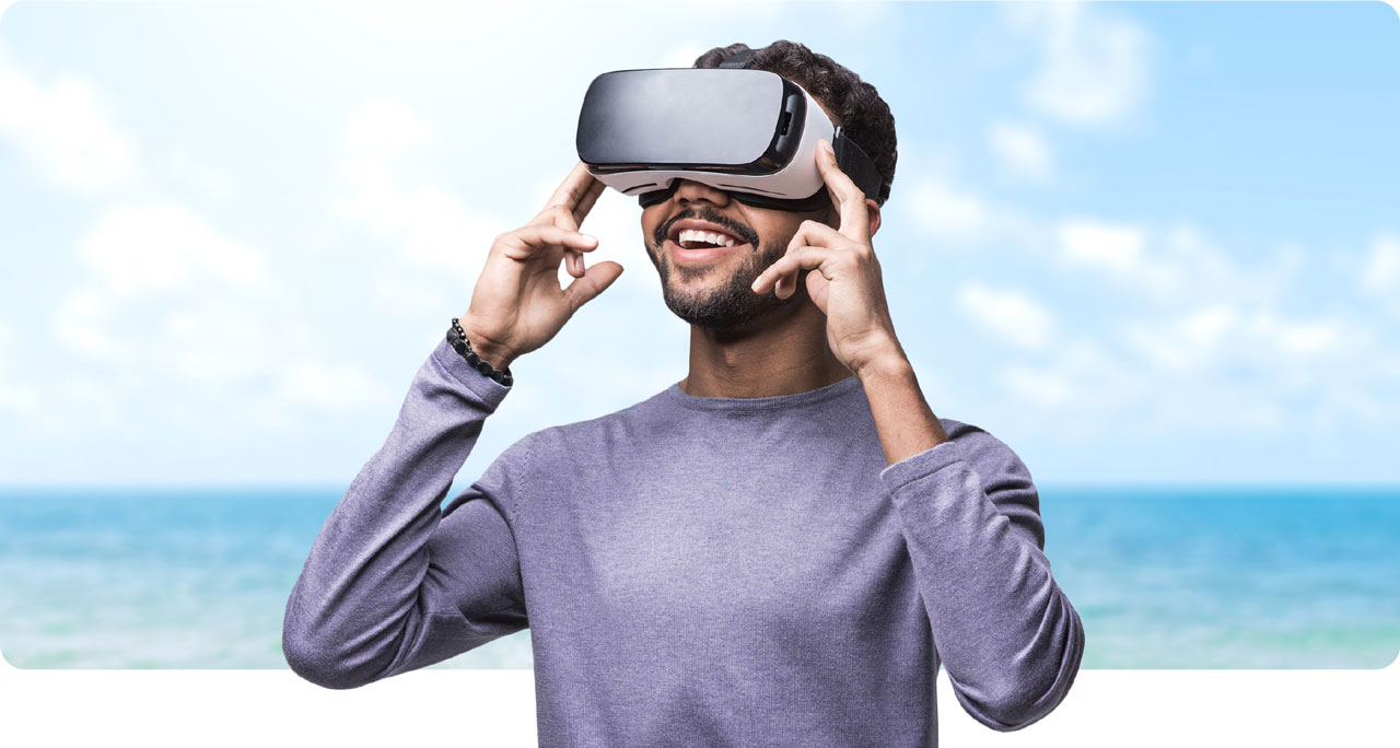 Photo montage of man looking through VR goggles with a serene ocean behind him