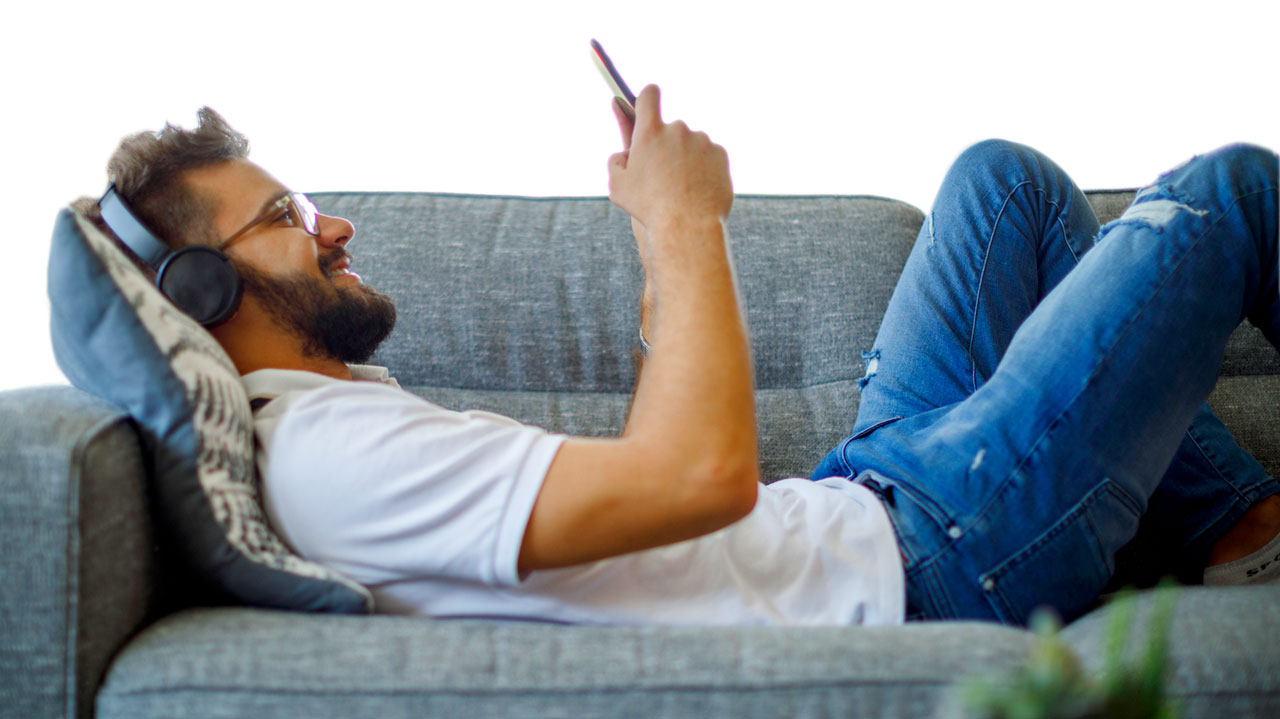 Image of man laying on sofa, looking on his phone