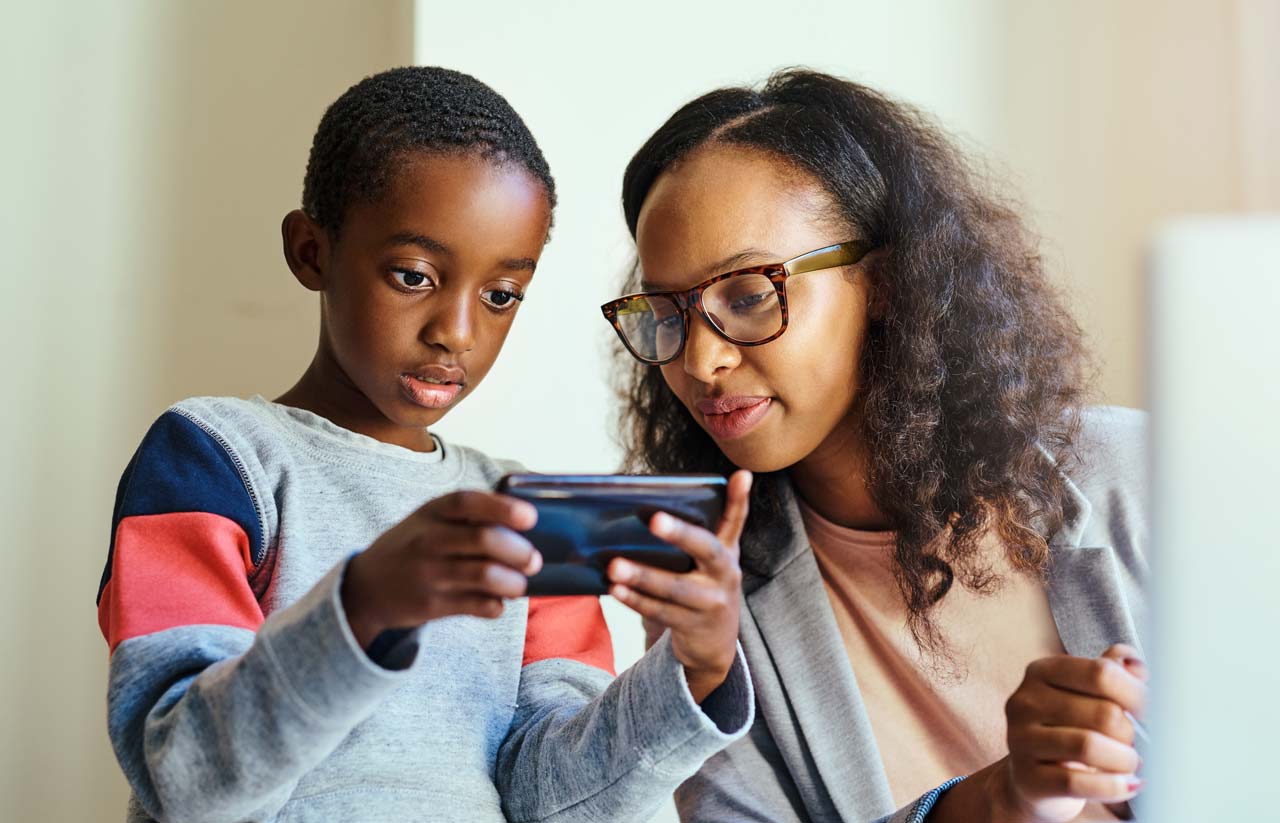 Photo of young boy showing his smart phone to his mother