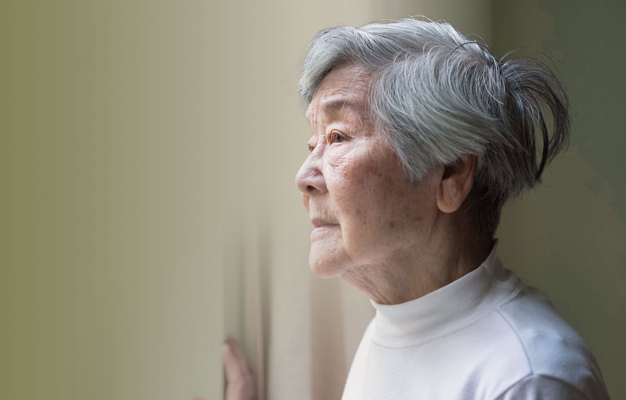 photo of senior woman looking out a window pensively