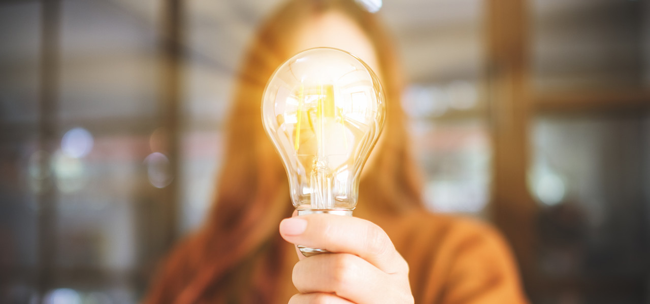 photo of woman holding a shining light bulb