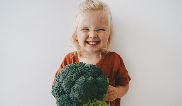 Photo of young girl holding a giant broccoli