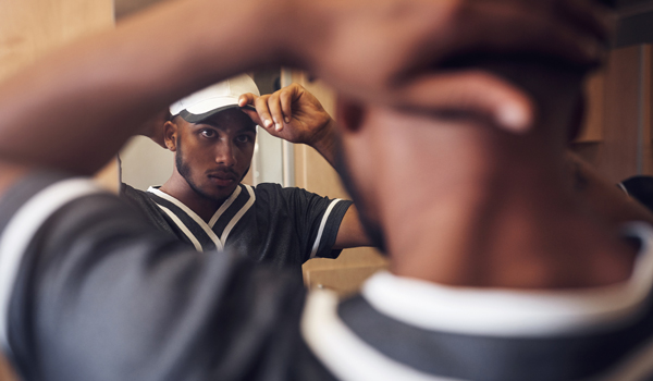 Photo of man adjusting hat in the mirror