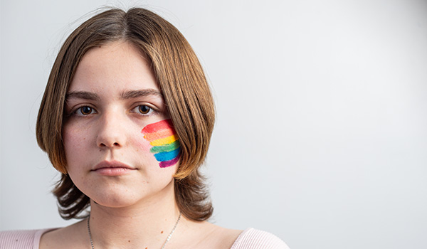 photo of teen with a rainbow flag painted on their cheek