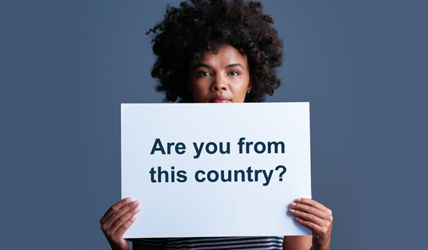 Black woman holding a sign that says 'Are you from this country?'