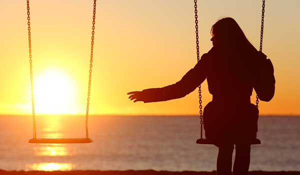 photo of a woman on a swing reaching out to an empty swing by her side