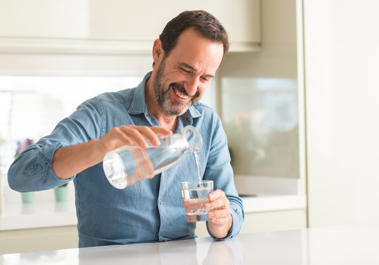 Photo of man pouring water into glass cup