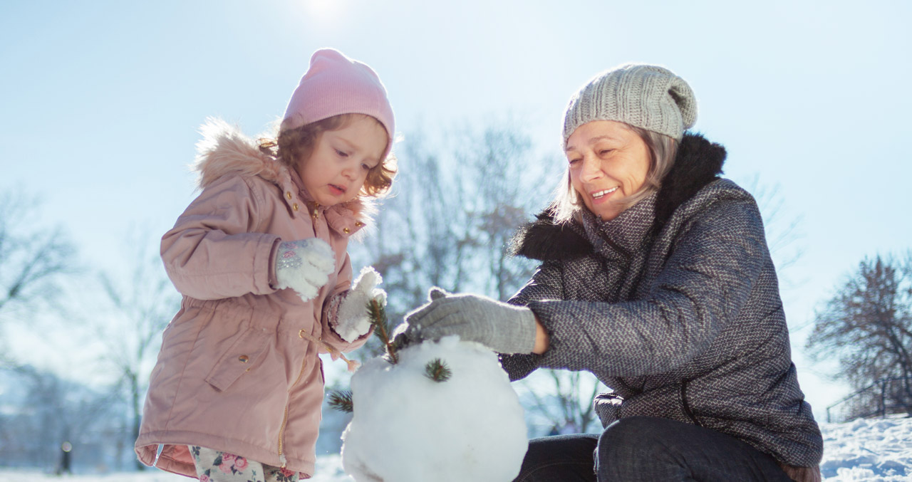 Photo of grandma and child building a snowman
