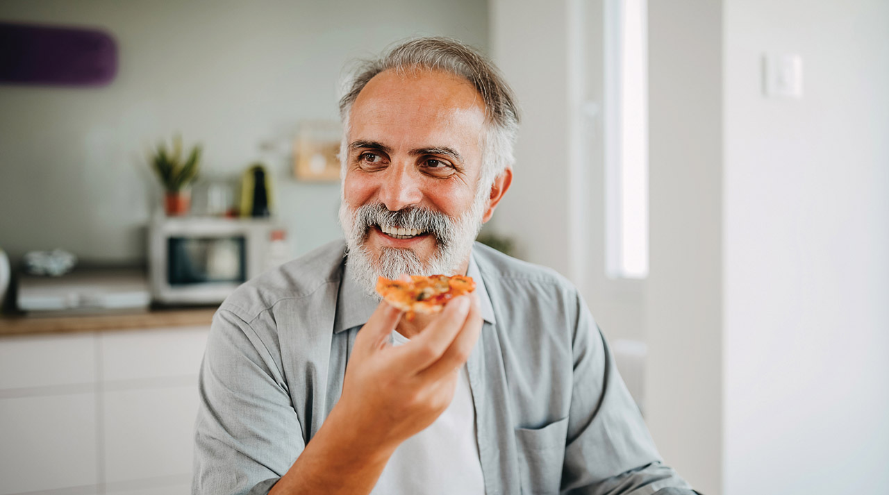 photo of mature man eating pizza