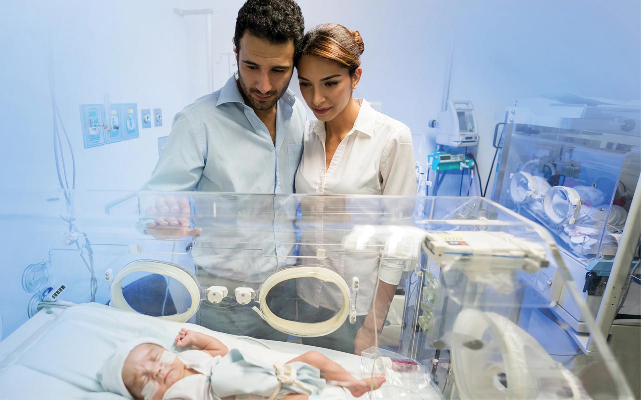 Image of couple looking at their baby in the NICU