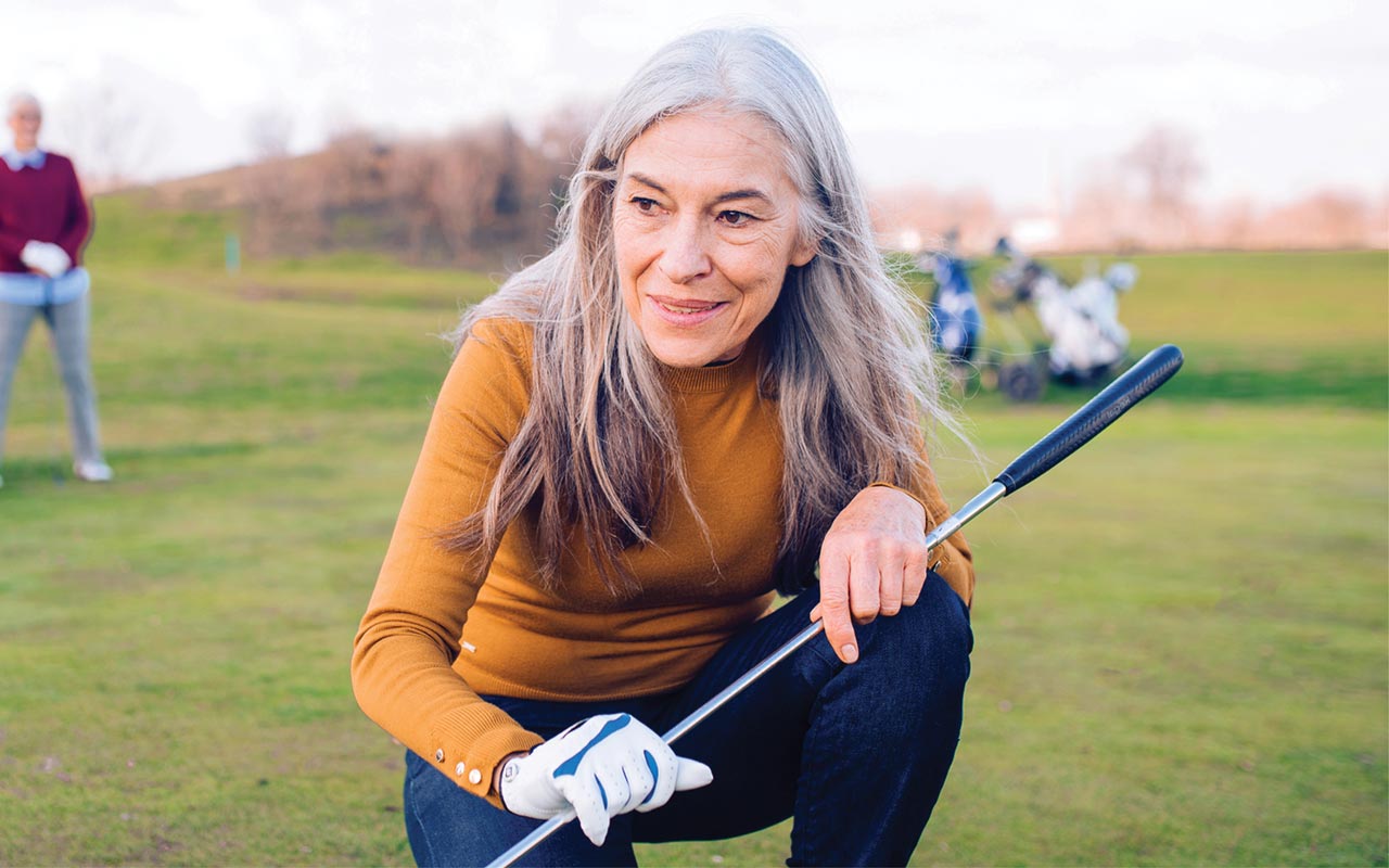 Image of senior woman kneeling on the golf course