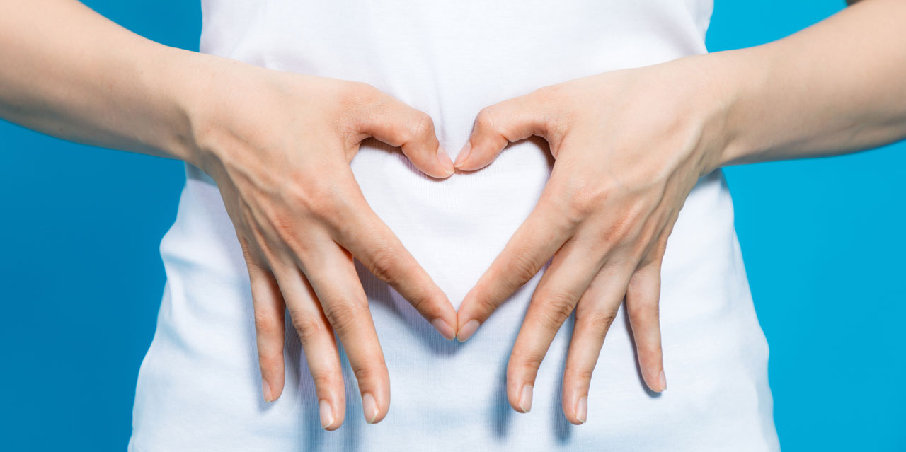 Photo of person doing a heart shape with their hands over their stomach